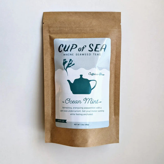 a kraft tea package with a white and blue label that reads "Cup of Sea - Maine Seaweed Teas - Ocean Mint" with a graphic of a solid blue tea kettle with seaweed shaped steam rising out of the spout