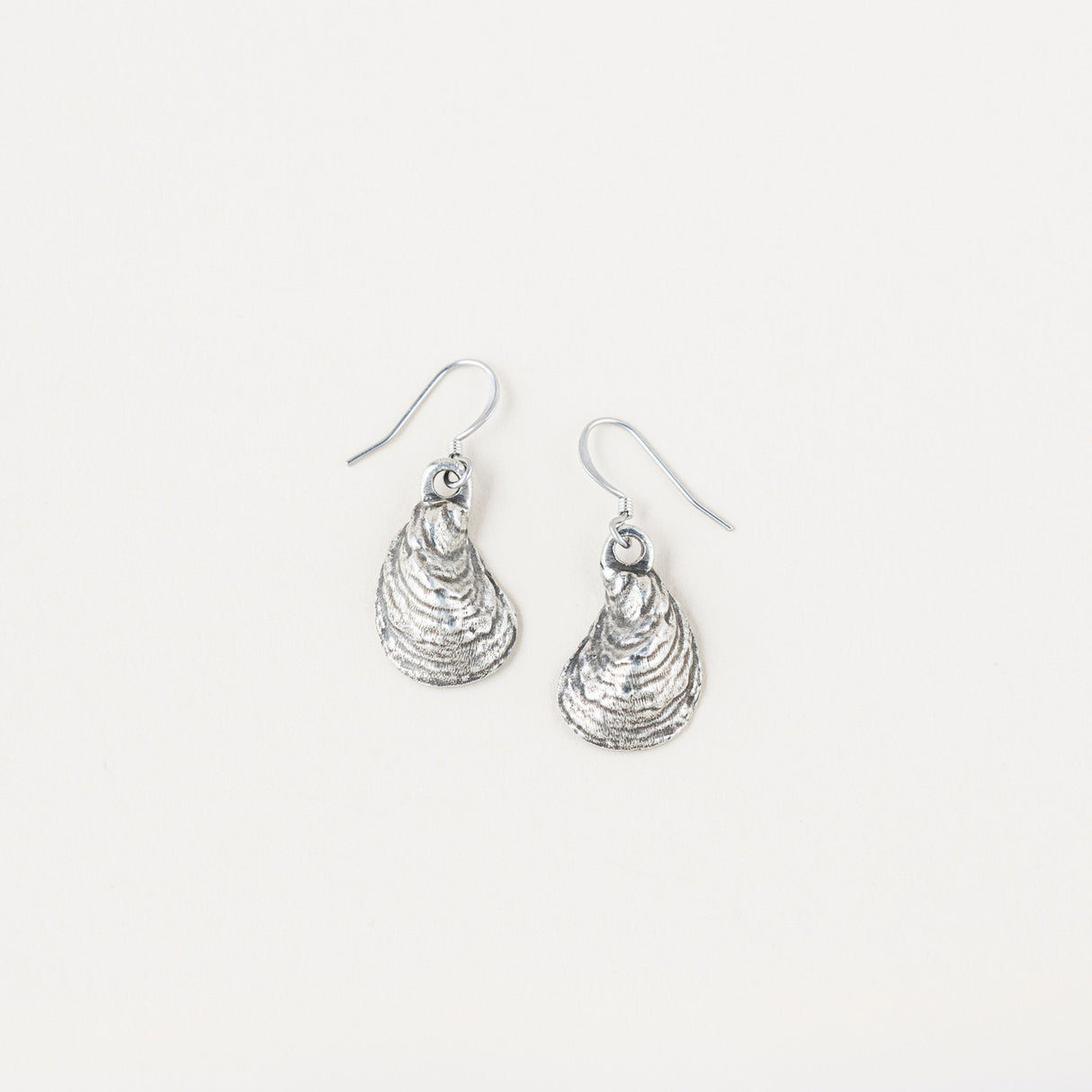 a pair of pewter oyster shell shaped earrings on a white background