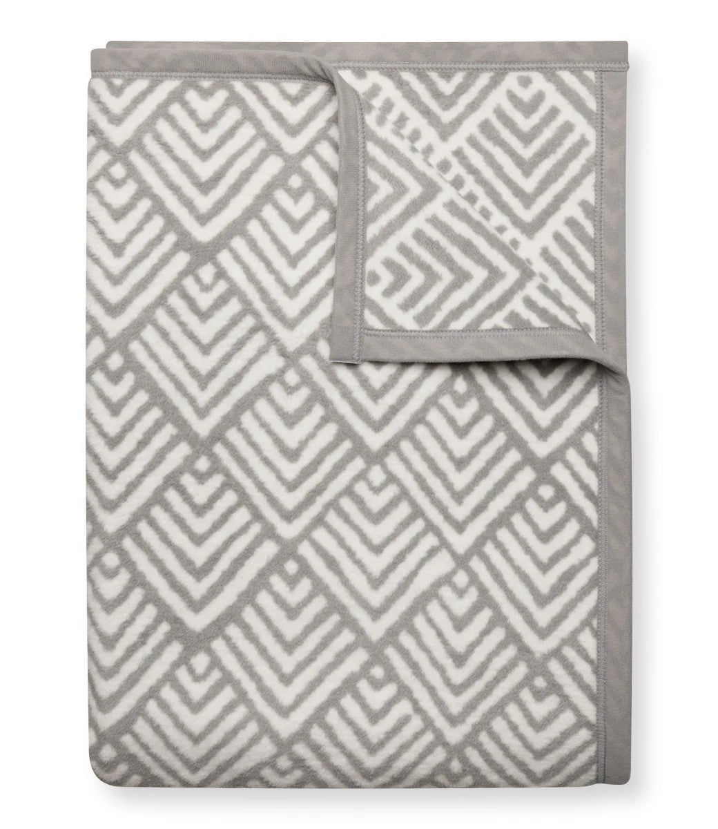 A folded Oyster Cove Diamonds Grey blanket with the top right corner folded over to show the reverse of the design
