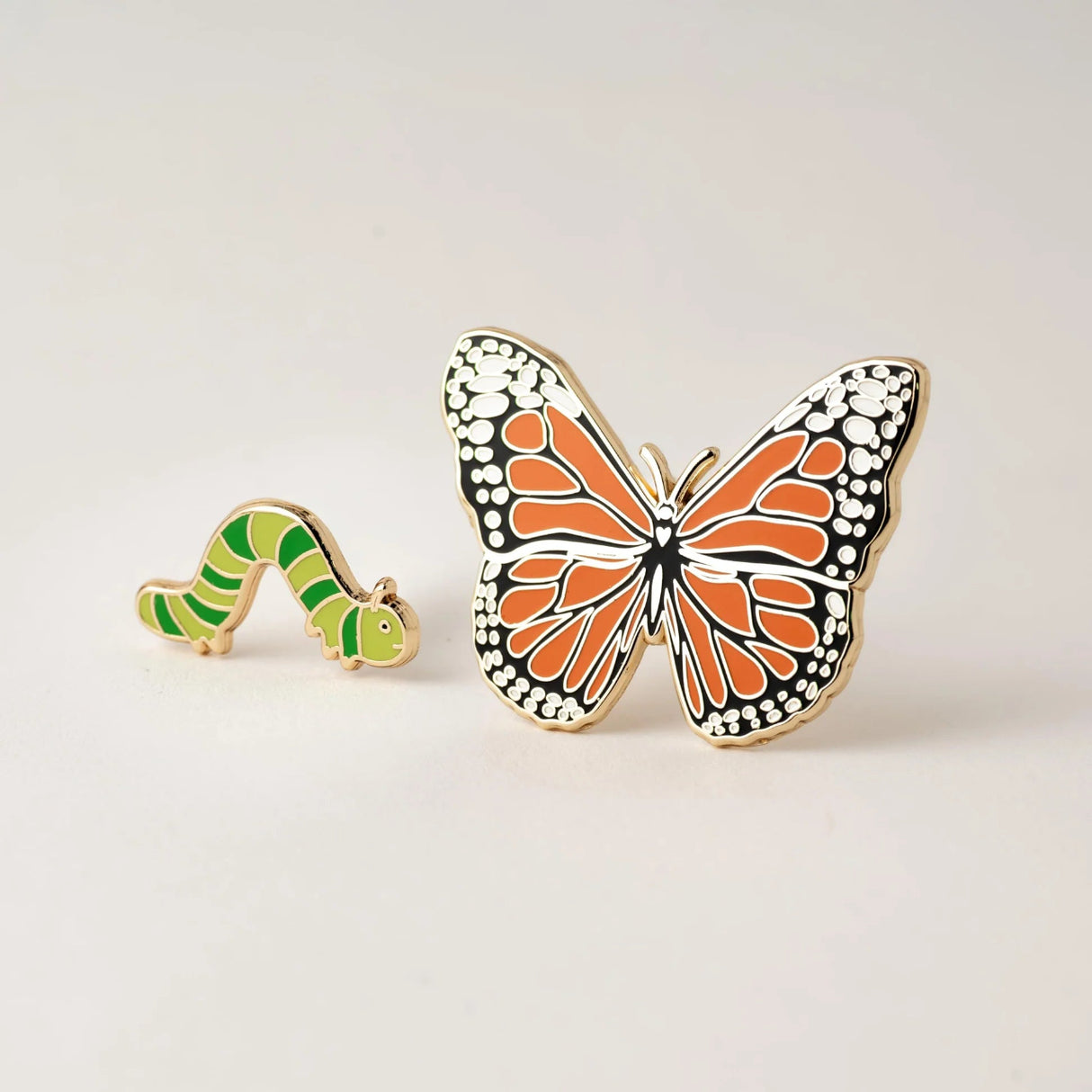 Butterfly and caterpillar pins on a light gray background