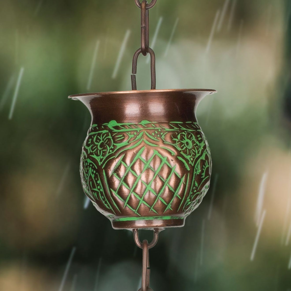 a close up of a single pot from the patina pot rain chain with a rainy garden in the background