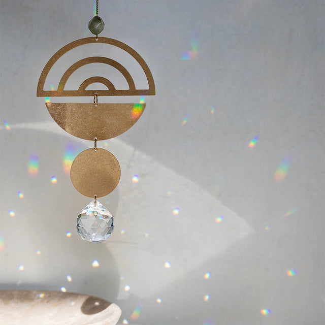 the rainbow suncatcher hanging in a room showing the suns rays reflecting tiny rainbows on the walls behind it