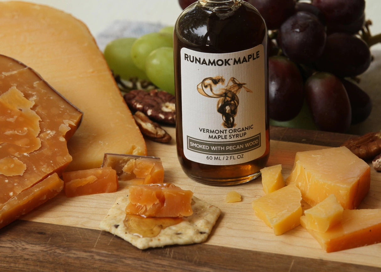 a bottle of smoked maple syrup on a cheese board with cheese and crackers to show how to pair the syrup with cheese