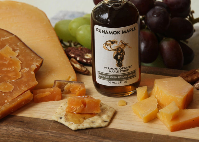 a bottle of smoked maple syrup on a cheese board with cheese and crackers to show how to pair the syrup with cheese