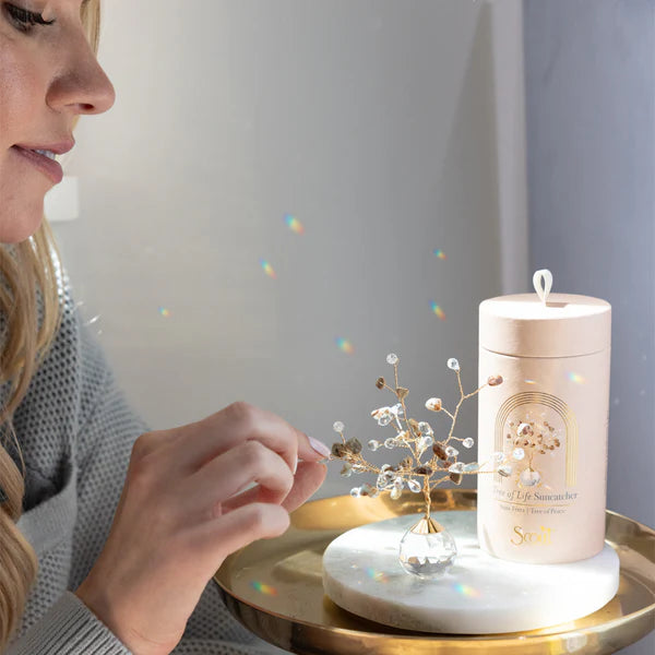 a model arranging the branches on her tree of life suncatcher on a sunlight side table
