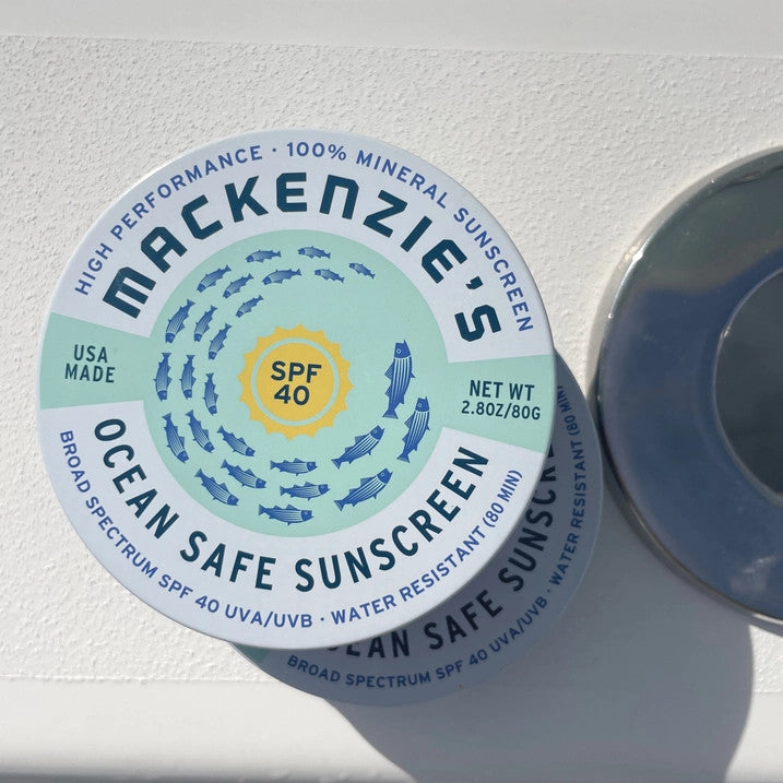a tin of ocean safe sunscreen on a white boat surface