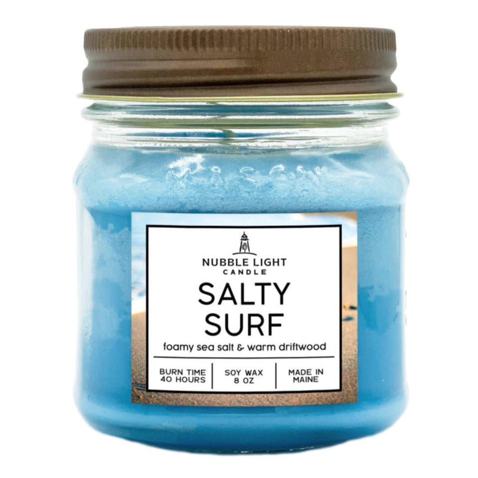 a sky blue candle in a mason jar with brown lid and text on the label that reads "Salty Surf: foamy sea salt & warm driftwood"