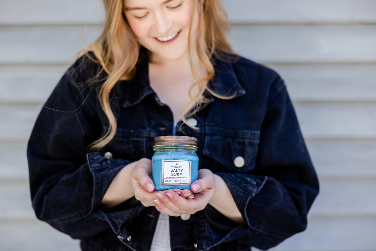 a model cradling a Salty Surf candle in her hands