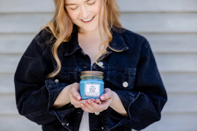 a model cradling a Salty Surf candle in her hands