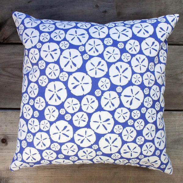 cornflower blue pillow with repeated sand dollar design on a wood surface