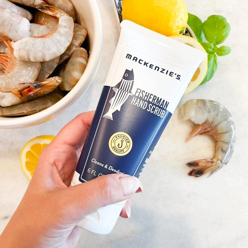 a hand holding a bottle of Fisherman Hand Scrub above a table of seafood
