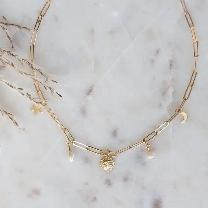 a gold paperclip chain with 14k gold fill charms of the sun, moon, and stars paired with delicate freshwater pearls