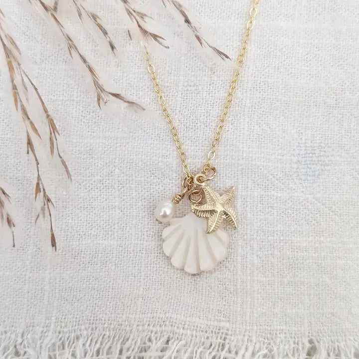 a charm necklace with a radiant mother of pearl seashell, a 14k gold fill starfish charm, and a lustrous freshwater pearl, all beautifully suspended on an 18" 14k gold fill chain