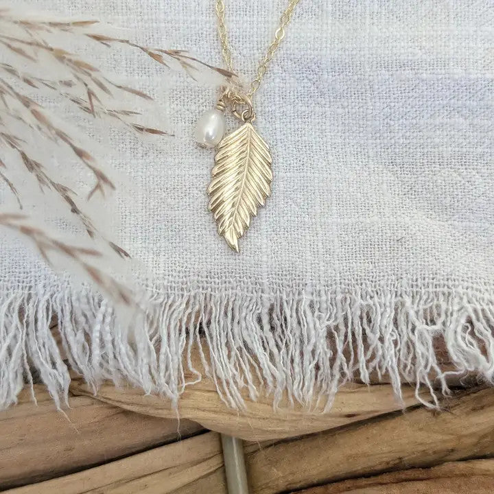 a charm necklace with a 14k gold fill leaf charm, and a lustrous freshwater pearl suspended on an 18" 14k gold fill chain