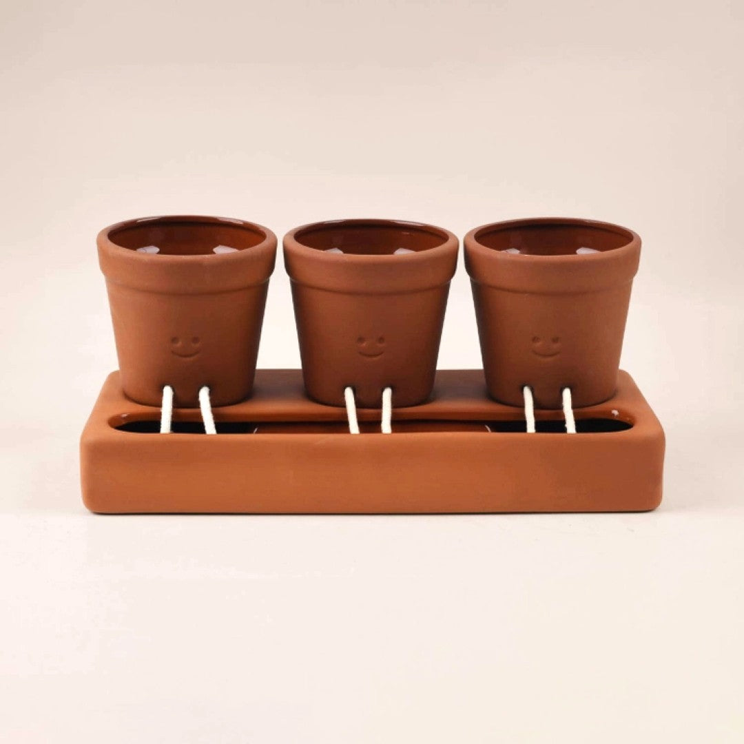 Set of three terracotta pots with (smiley face) designs on a matching brown tray.