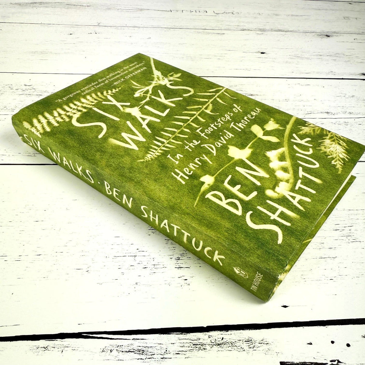 Six Walks book shown at a slight side angle on a white wood surface showing the spine of the book
