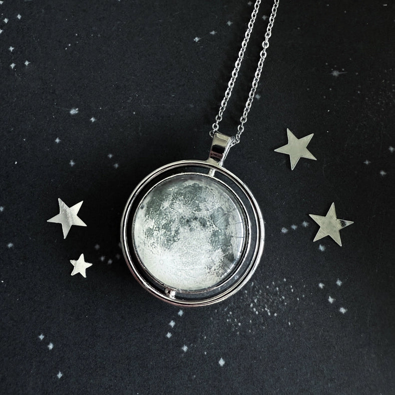 Necklace with a moon-phase pendant on a dark background with star decorations