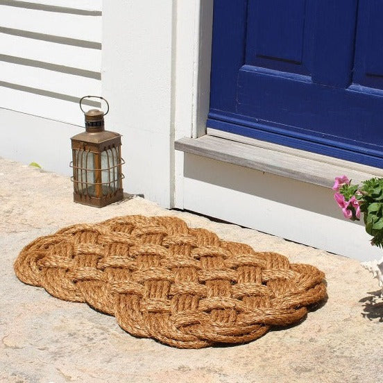 a hand-woven nautical entry mat in manila rope in front of a doorway