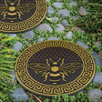 two garden stepping stones with bee design and honeycomb background installed in a stony garden pathway