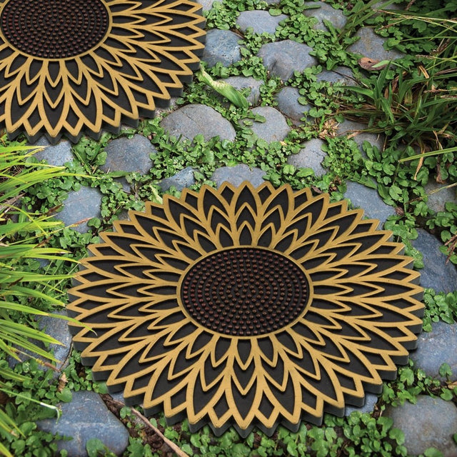 two garden stepping stones with sunflower design installed in a stony garden pathway