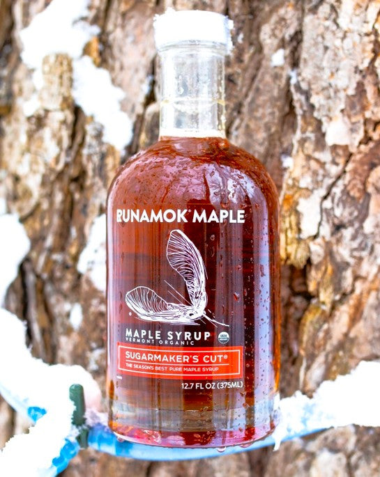 a bottle of sugarmaker's cut resting on a maple tap on a snowy maple tree