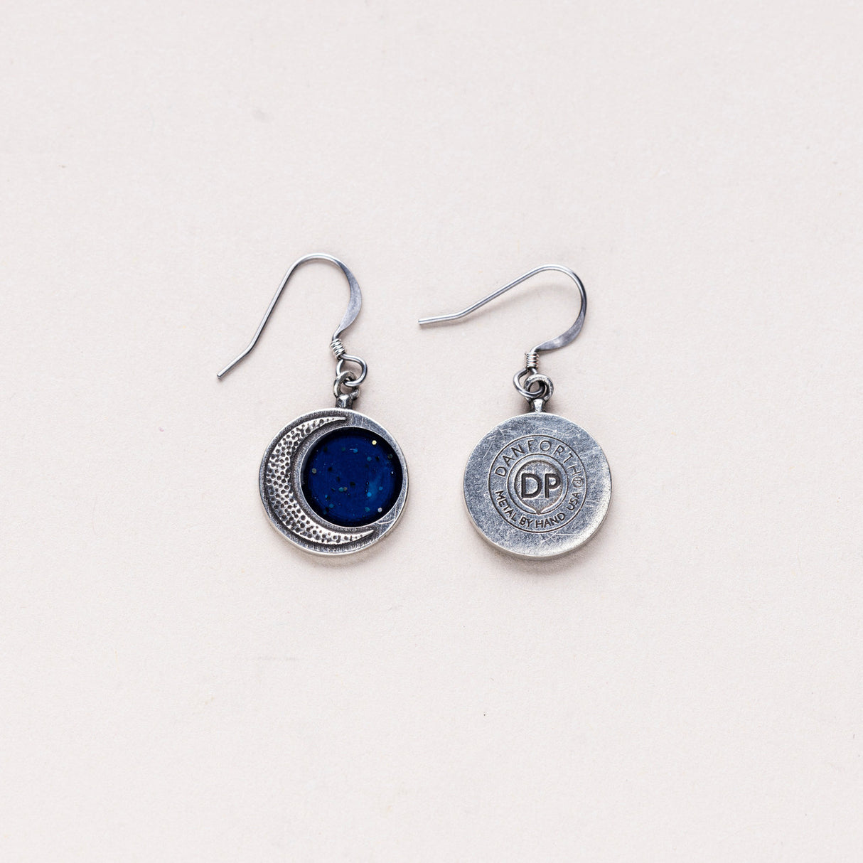 Back view of the Crescent Moon Earrings displaying the maker's mark stamped on the pewter, indicating the handcrafted quality of the piece.