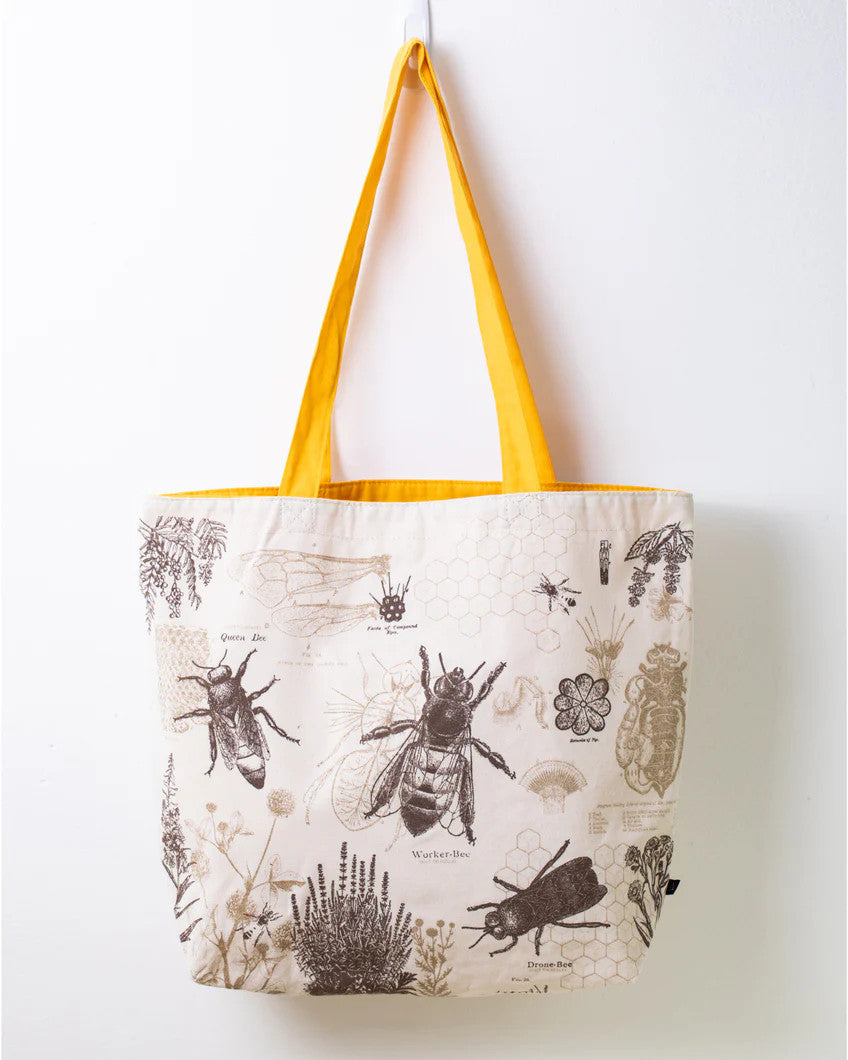 side one of the honey bee tote; a white tote bag with yellow straps covered in vintage illustrations and academic diagrams of the honey bee
