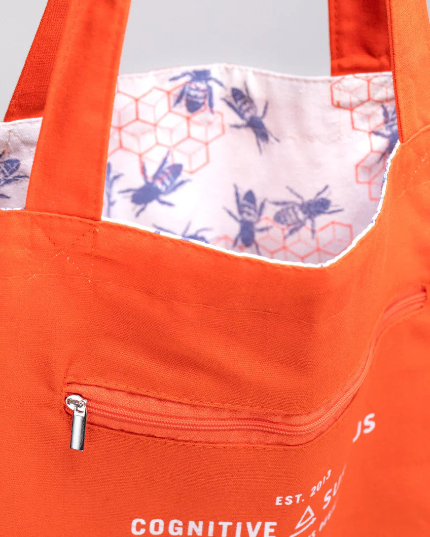 a close up of the tote near the handles showing the bag reversed so the bee hive print is on the inside of the tote and the outside is now a vibrant orange