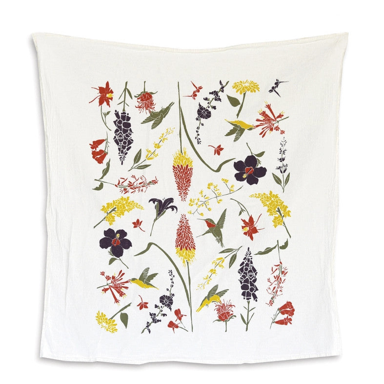 A white tea towel with botanical illustrations of flowers that hummingbirds enjoy with some ruby throated hummingbirds flitting from flower to flower