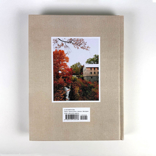 Beige book with a postcard featuring a scenic view of trees and a building on a white background