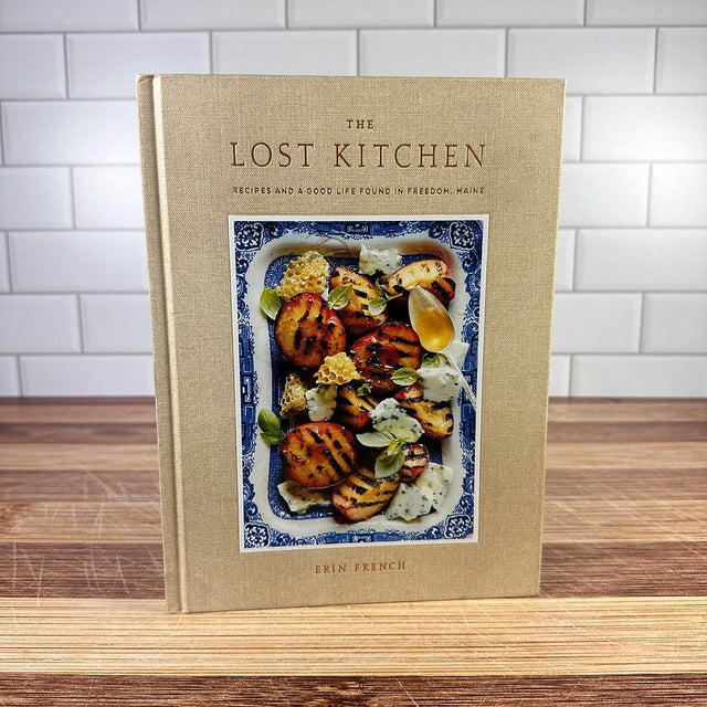 Cookbook titled 'The Lost Kitchen' on a wooden surface with a tiled wall background