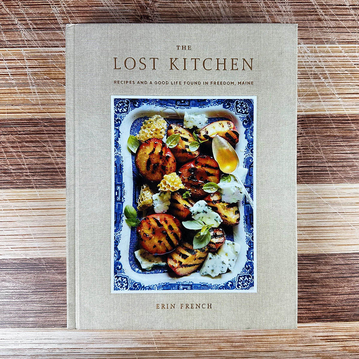 Cookbook titled 'The Lost Kitchen' by Erin French on a wooden surface