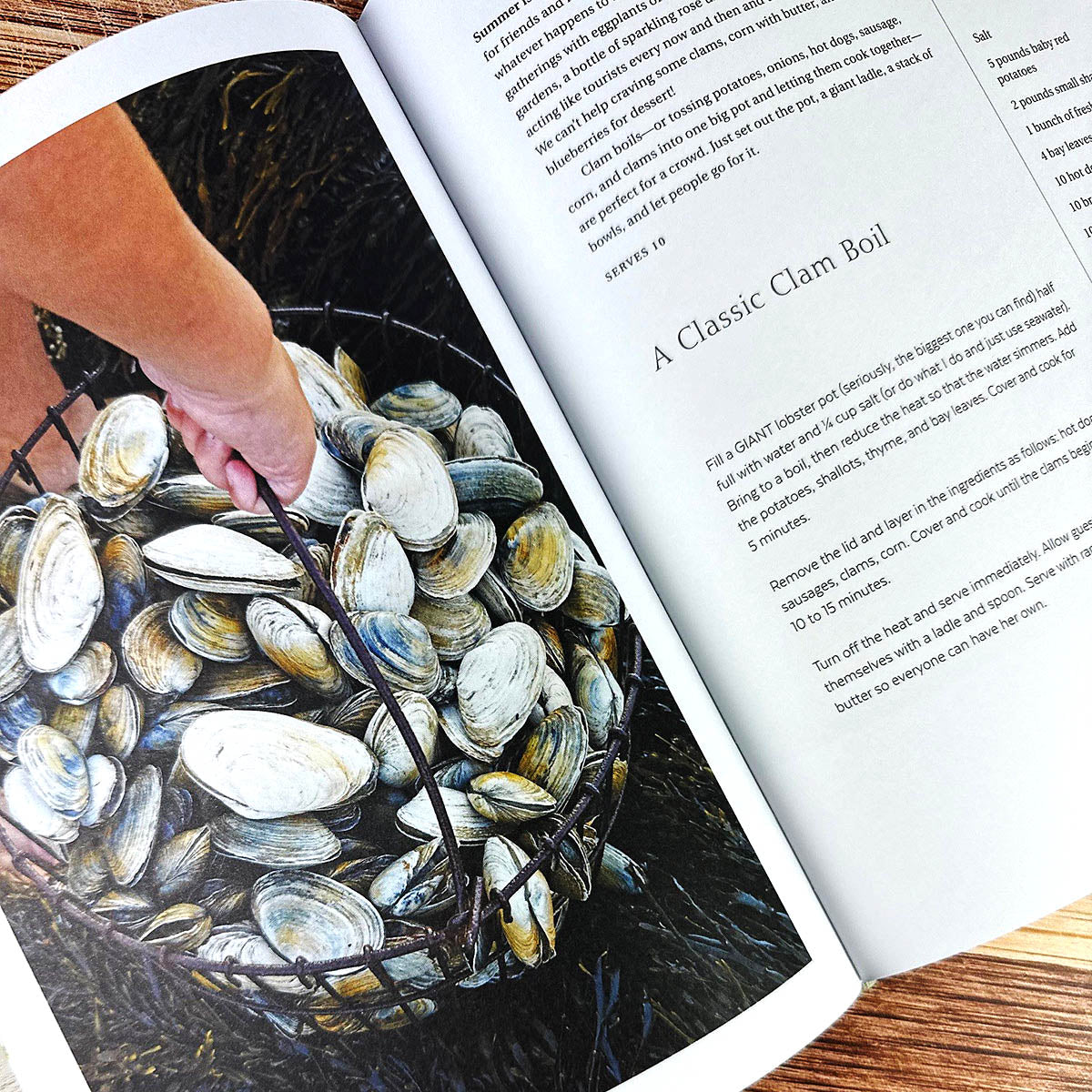 Open book with a hand holding clams and a recipe for a clam boil.