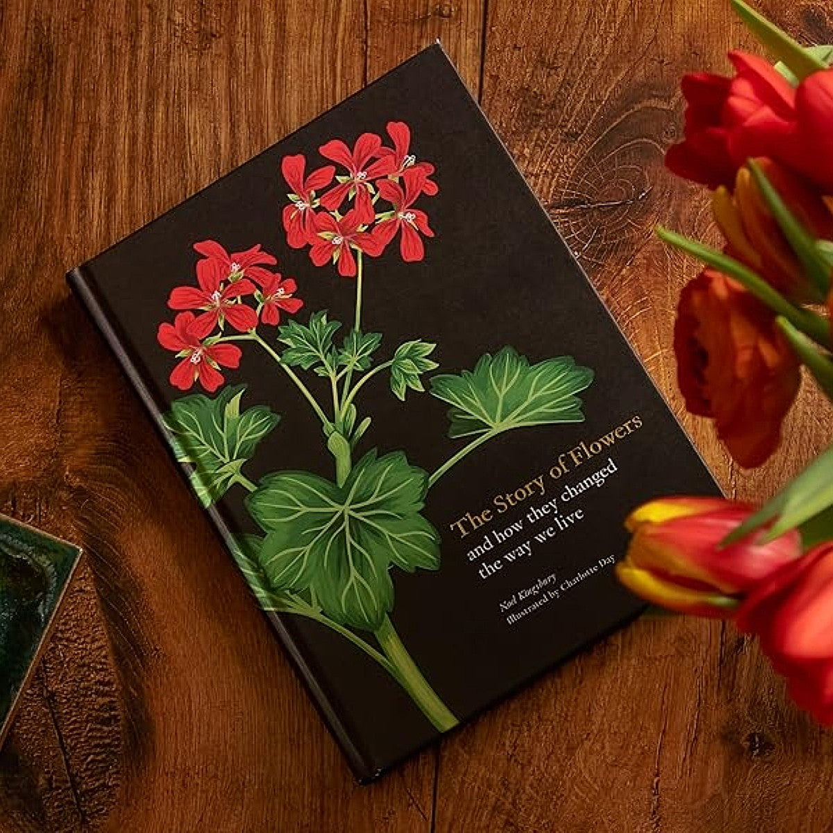 The Story of Flowers book on a wooden surface with a bouquet of tulips near the book