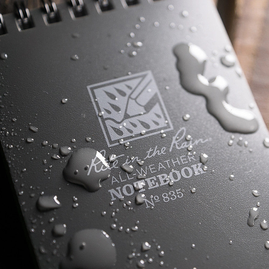 a close up of the top spiral notebook with water beading on the surface to show its weather-proof nature