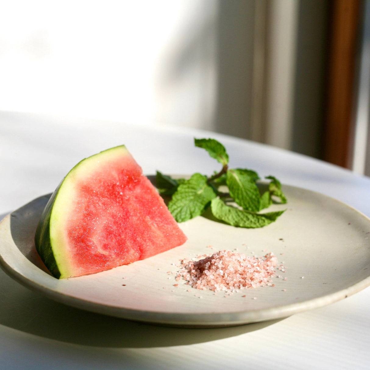 a plate with the fresh ingredients used in this shrub: watermelon, mint, and Himalayan salt