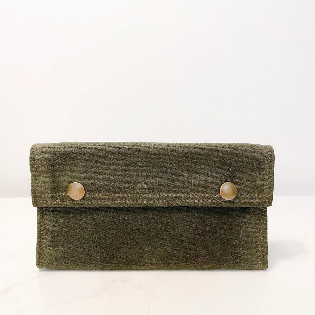 a green waxed canvas fly fishing wallet with brass snap closures