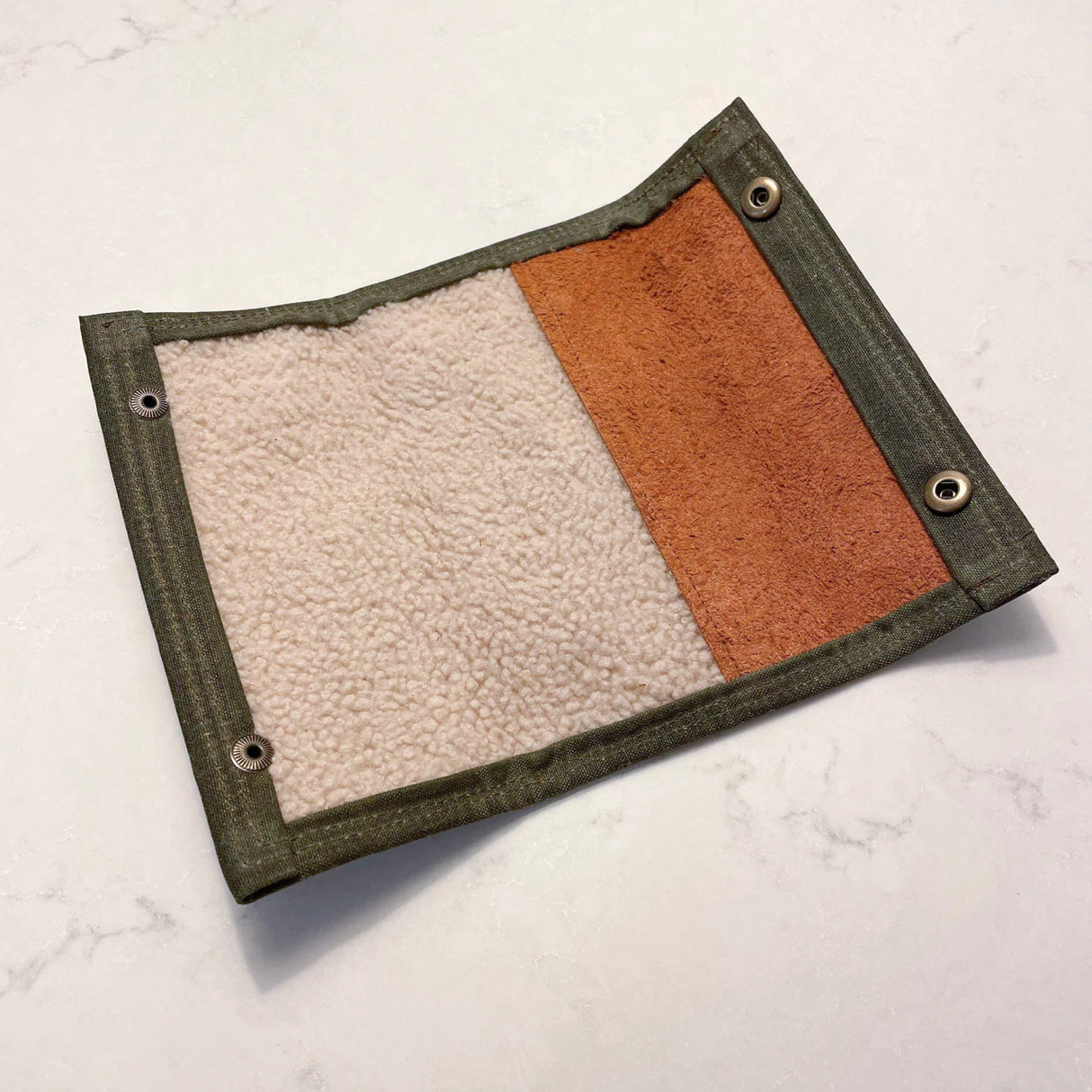 the fly-fishing wallet shown open exposing the shearling liner the holds the flies in place