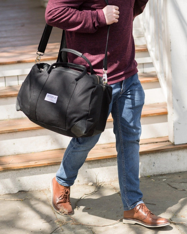 a model with the black weekender bag slung over one shoulder