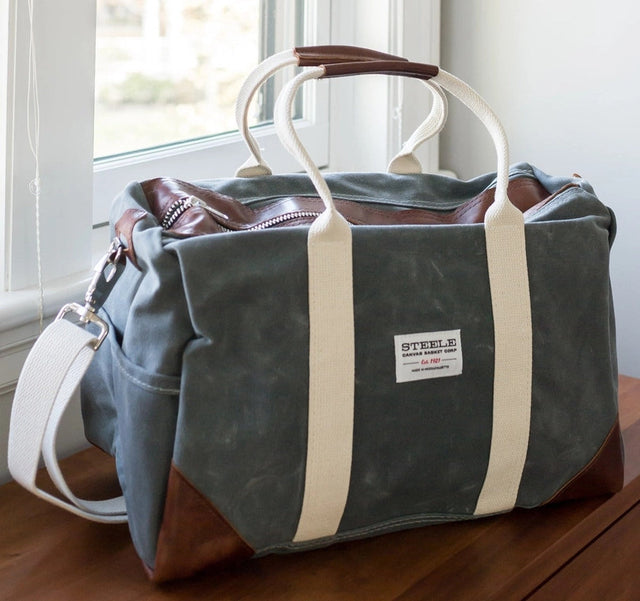 the waxed briquette weekender bag all packed next to a door, ready for adventure