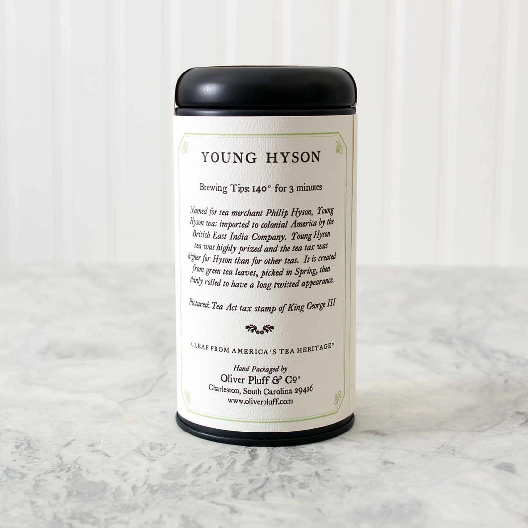 tin of Young Hyson tea showing the label on the back of the tea that details brewing tips along with history of the tea. Tin sits on a white marble surface with white background