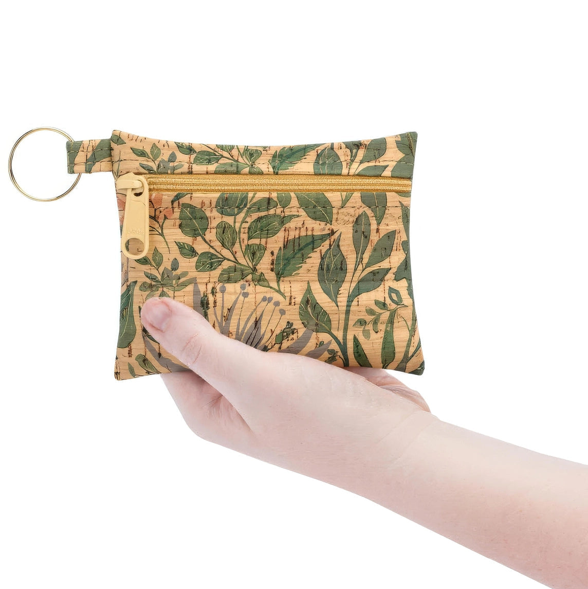 Hand holding a small pouch with leaf pattern on a white background