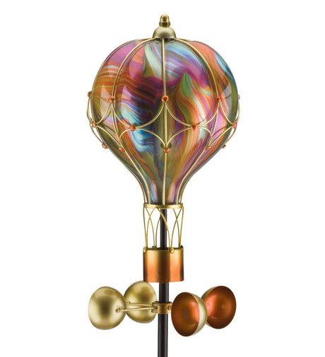 Orange swirl balloon spinner solar stake. The image features a decorative garden stake with a spiral, orange-colored hot air balloon spinner that rotates in the wind. The spinner has a vibrant orange hue with a marbled effect, and it is attached to a black stake with a solar-powered light at the top.