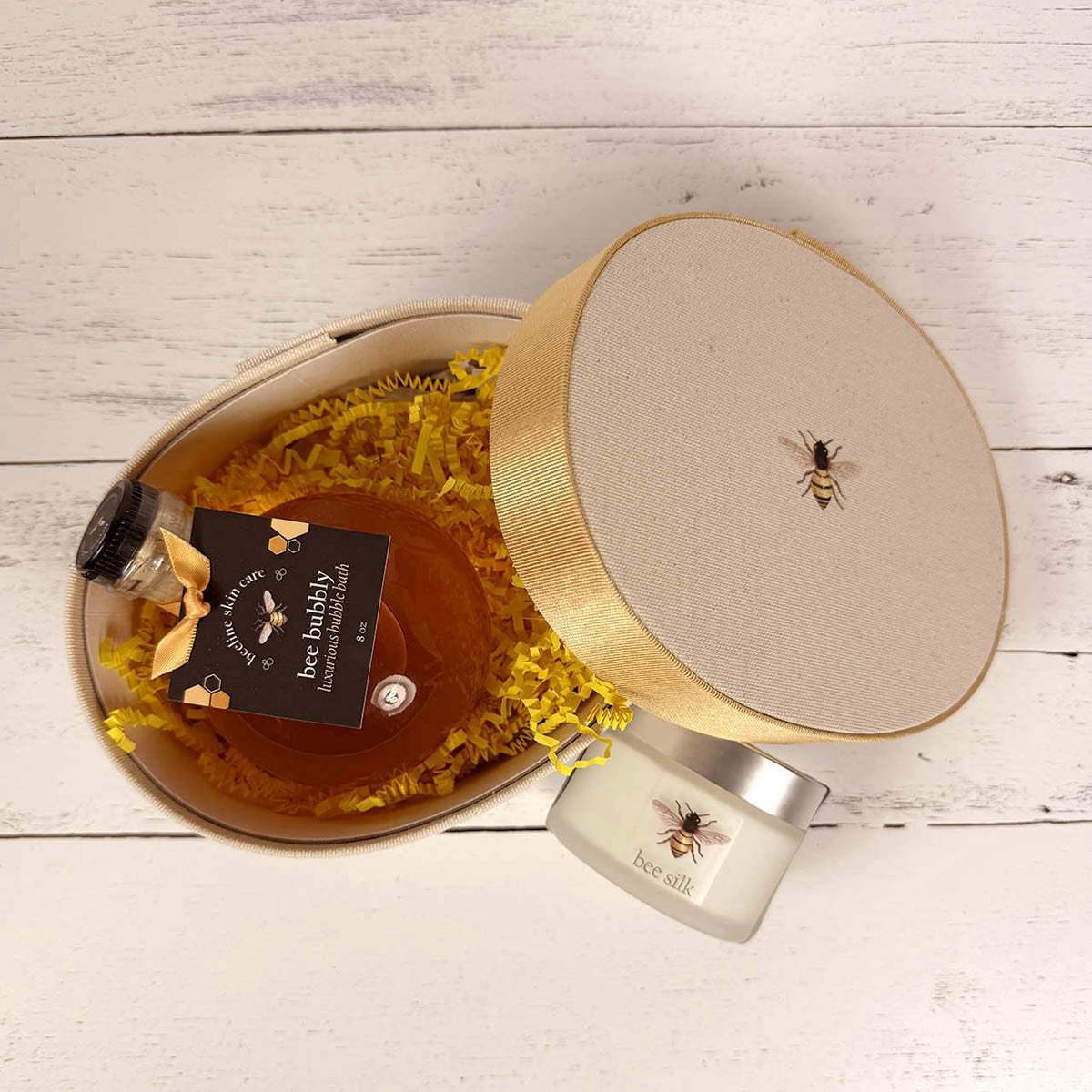a above view of the open hat box with the Bee Bubbly bottle inside and the Bee Silk next to it on the outside of the box