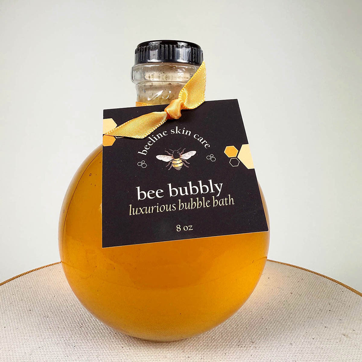 a close up of the Bee Bubbly bubble bath in its spherical glass bottle