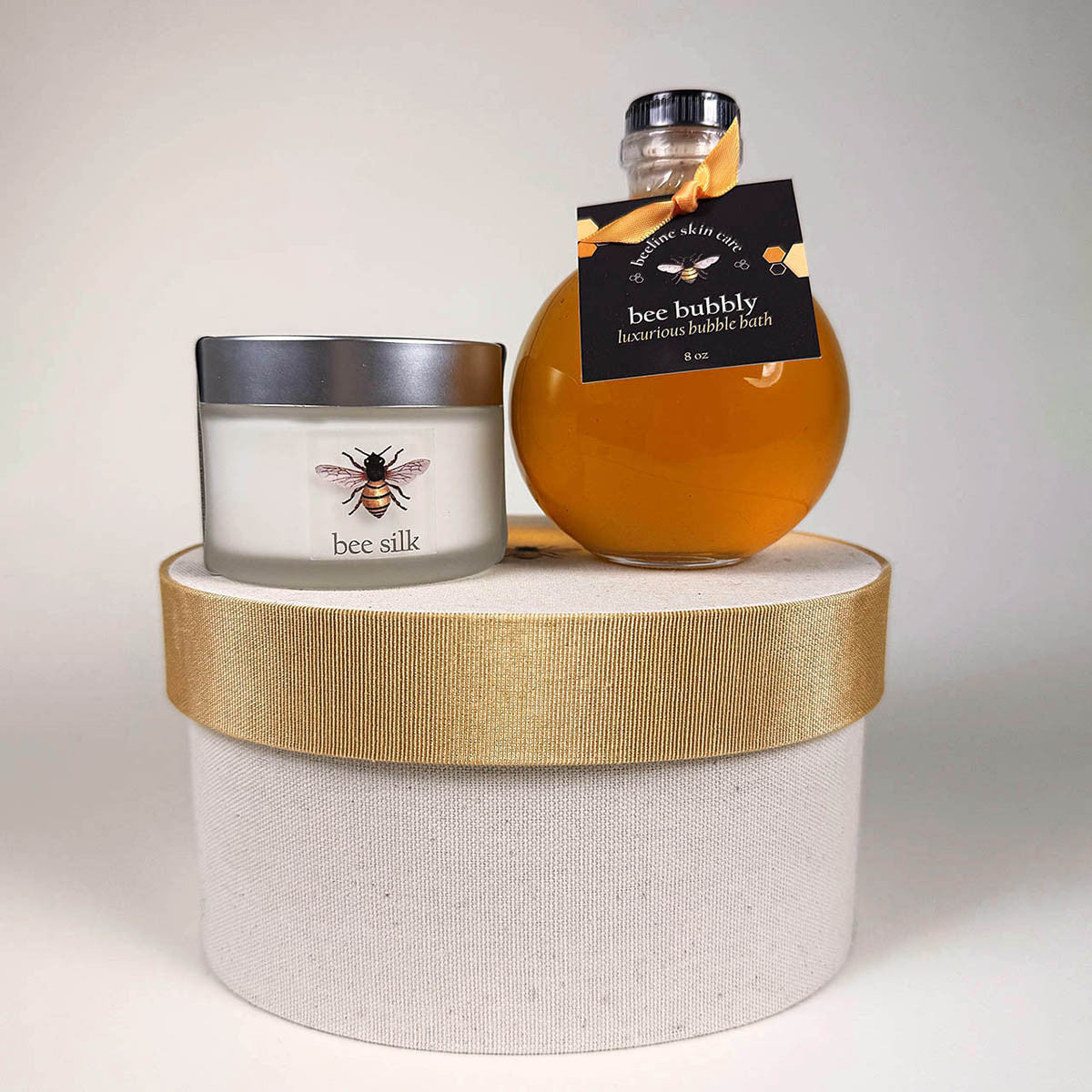the jar of Bee Silk and bottle of Bee Bubbly set atop of the closed hat box