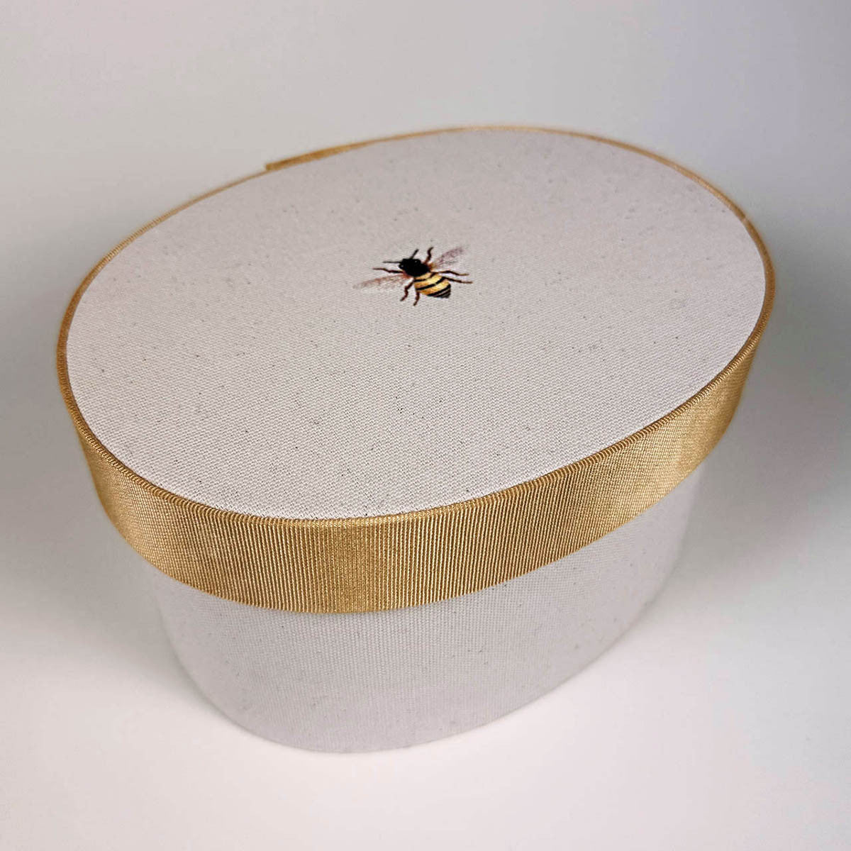 the beekeeper box hat box with bee emblem in the center of the box lid on a white background