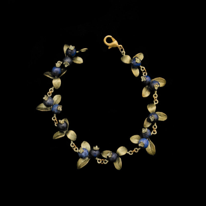 a delicate bracelet adorned with cast bronze blueberry leaves and lapis berries, the bracelet is clasped and forming a circle