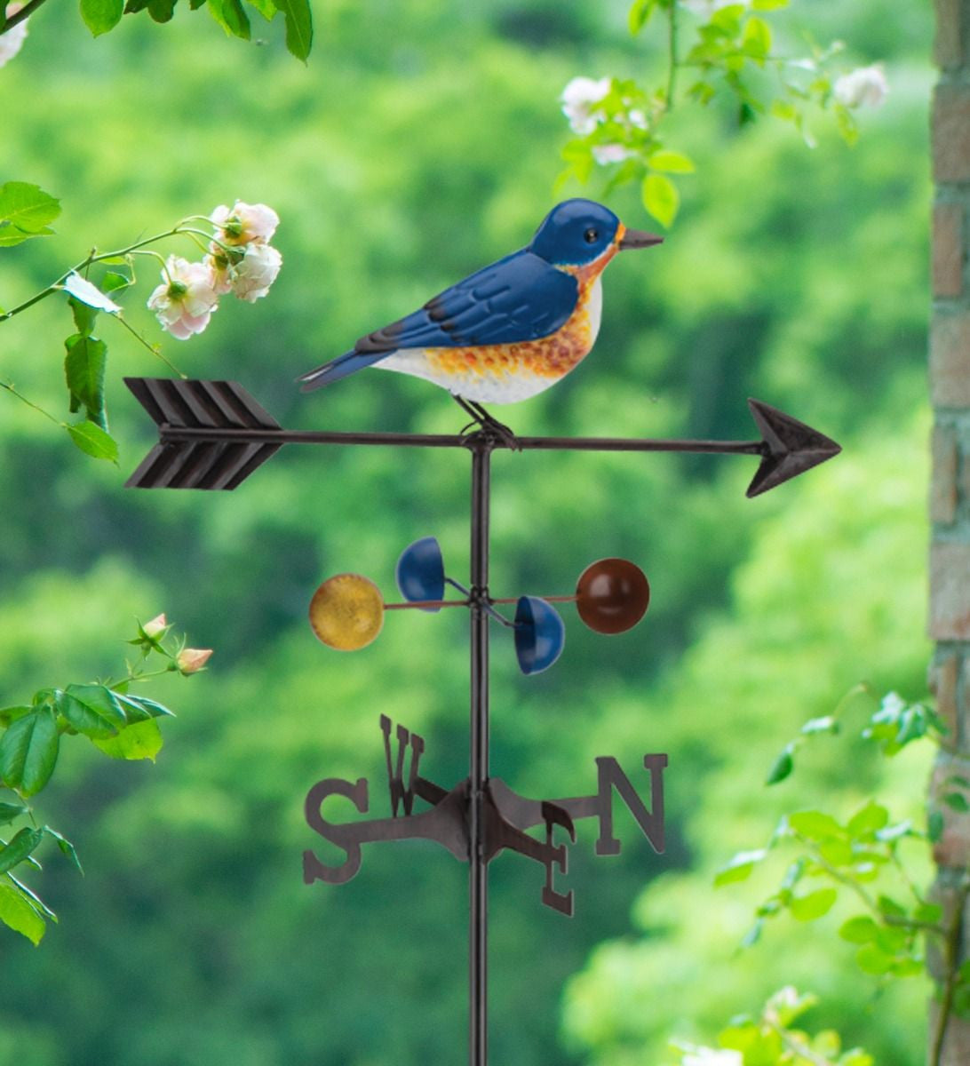 close up of Bluebird weathervane stake displayed in a garden setting, surrounded by  greenery