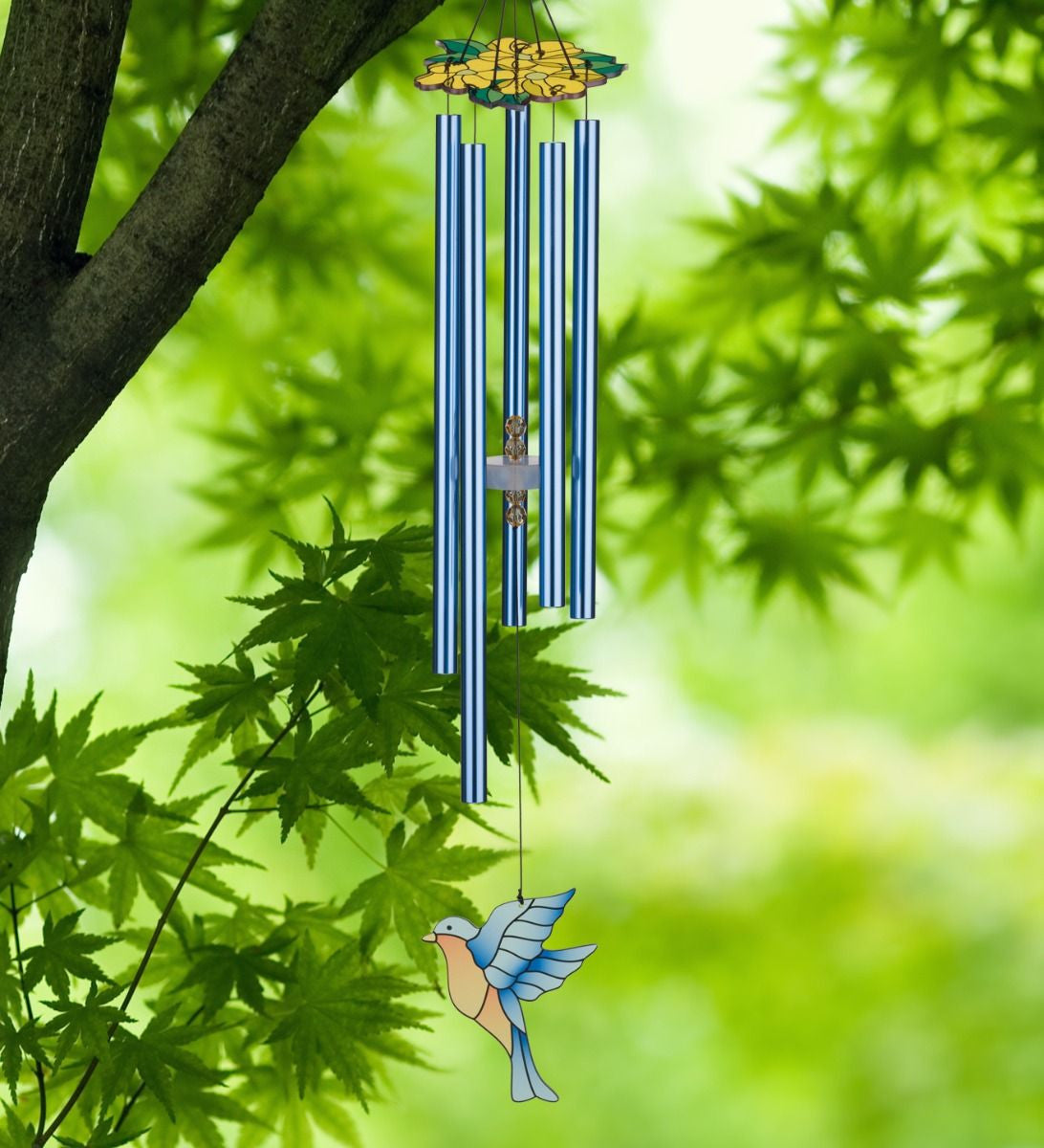 Bluebird Chimes with yellow floral canopy, blue chime tubes, and stained glass style bluebird sail seen hanging from a tree